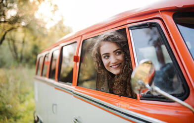 Ein fröhliches junges Mädchen, das auf einer Fahrt durch die Landschaft aus einem Auto schaut. - HPIF24734