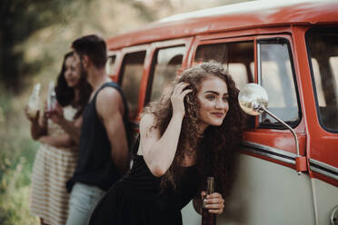 A group of young friends with drinks standing outdoors on a roadtrip through countryside, holding bottles. - HPIF24752