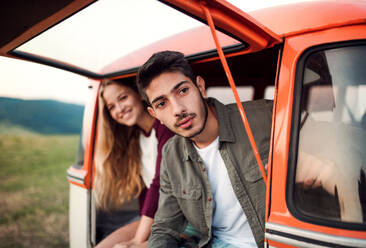 Ein junges Paar auf einem Roadtrip durch die Landschaft, sitzend in einem Retro-Minivan. - HPIF24784