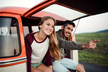 A young couple on a roadtrip through countryside, sitting in retro minivan. - HPIF24785