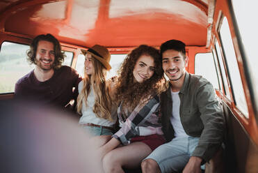 Eine Gruppe junger Freunde macht einen Roadtrip durch die Landschaft und sitzt in einem Retro-Minivan. - HPIF24810