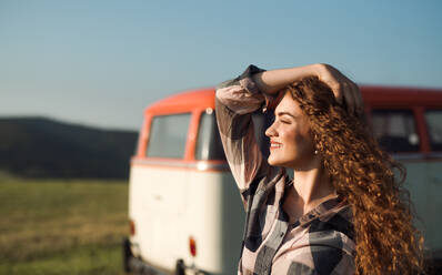 Ein junges Mädchen auf einem Roadtrip durch die Landschaft, das neben einem Minivan steht. Kopierraum. - HPIF24814