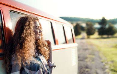 A young girl on a roadtrip through countryside, leaning on a retro minivan, eyes closed. Copy space. - HPIF24815