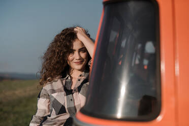 A young girl on a roadtrip through countryside, standing by a minivan. Copy space. - HPIF24817