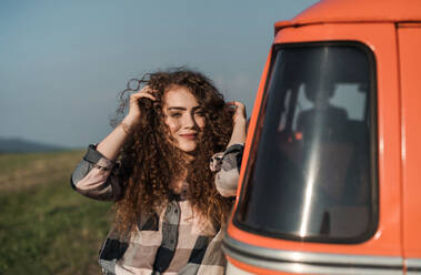 A young girl on a roadtrip through countryside, standing by a minivan. Copy space. - HPIF24818