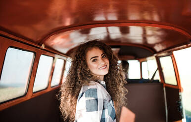Ein fröhliches junges Mädchen in einem Auto auf einem Roadtrip durch die Landschaft. - HPIF24822
