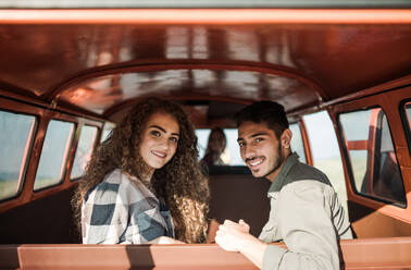 Eine Gruppe junger Freunde macht einen Roadtrip durch die Landschaft und sitzt in einem Retro-Minivan. - HPIF24823