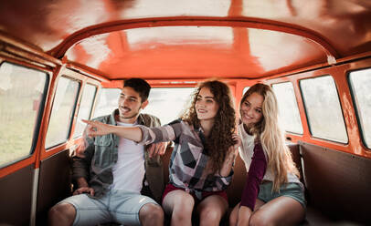 Eine Gruppe junger Freunde macht einen Roadtrip durch die Landschaft und sitzt in einem Retro-Minivan. - HPIF24827