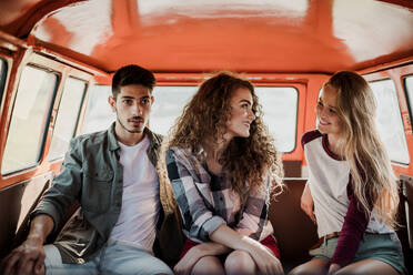 A group of young friends on a roadtrip through countryside, sitting in a retro minivan. - HPIF24828