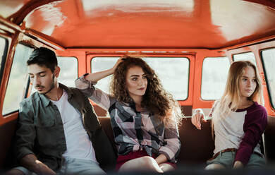 A group of young friends on a roadtrip through countryside, sitting in a retro minivan. - HPIF24829