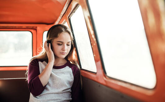 Freunde auf einem Roadtrip durch die Landschaft, ein Mädchen mit Kopfhörern, das Musik hört. Raum kopieren. - HPIF24833
