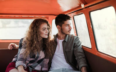 Ein junges Paar auf einem Roadtrip durch die Landschaft, sitzend in einem Retro-Minivan. - HPIF24835