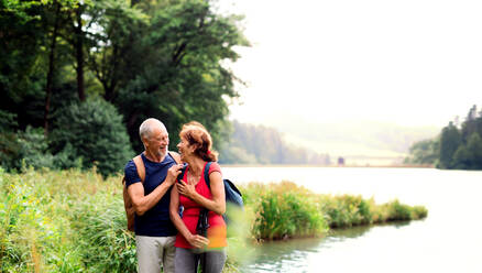 Ein älteres Touristenpaar auf einem Spaziergang in der Natur, stehend am See. Kopierraum. - HPIF24893