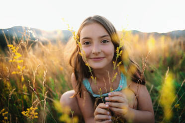 Ein Porträt eines glücklichen kleinen Mädchens im Gras in der Natur, das in die Kamera schaut. - HPIF24916