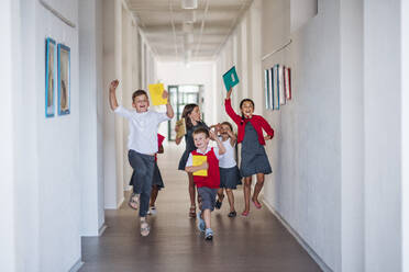 A group of cheerful small school kids in corridor, running and jumping. Back to school concept. - HPIF24947