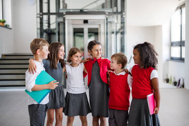 Eine Gruppe von fröhlichen kleinen Schulkindern, die im Korridor stehen, zurück zur Schule. - HPIF24952