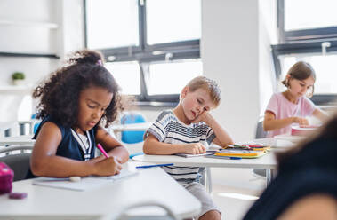 Ein kleiner müder und gelangweilter Schuljunge sitzt am Schreibtisch im Klassenzimmer und schläft. - HPIF24979