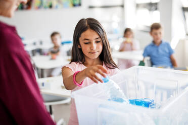 A teacher with small school kids in classroom learning about ecological waste separation. - HPIF25002