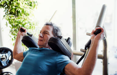 Ein konzentrierter älterer Mann beim Krafttraining im Fitnessstudio. - HPIF25026