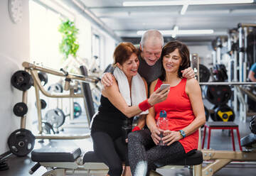 Aktive Senioren halten mit einem Selfie während einer Trainingspause im Fitnessstudio einen Moment der Freude und Fitness fest - HPIF25043