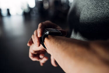 A midsection of man with smartwatch in gym measuring time while doing exercise. Copy space. - HPIF25065