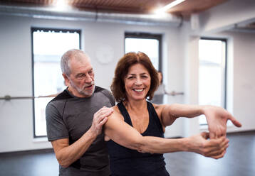 A cheerful senior woman in gym doing exercise with a personal trainer. - HPIF25092