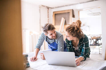 Man and woman worker with laptop in the carpenter workroom. Young couple working together. - HPIF25160