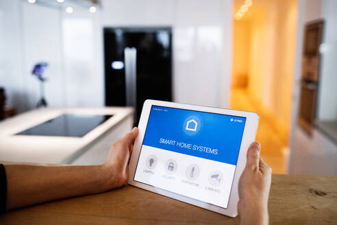 Männliche Hände halten ein Tablet mit einem intelligenten Haussteuerungssystem. - HPIF25216