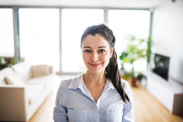 A portrait of a beautiful woman standing at home. - HPIF25240