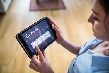 An unrecognizable woman holding a tablet with smart home control system. - HPIF25243