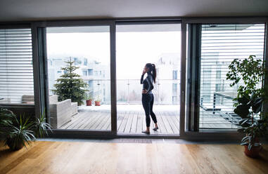 A woman standing by the window, holding smartphone and making a phone call. - HPIF25262