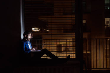 Ein gut aussehender Mann, der zu Hause oder nachts in einem Büro an einem Laptop arbeitet. - HPIF25268