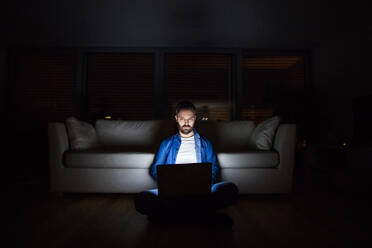 Ein gut aussehender Mann, der nachts zu Hause an seinem Laptop arbeitet. - HPIF25270