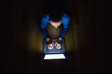 Ein Mann, der nachts zu Hause an einem Laptop arbeitet. Smart-Home-Steuerungssystem. Ansicht von oben. - HPIF25271