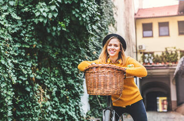 Young beautiful woman with bicycle standing in sunny spring town. - HPIF25288
