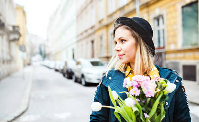 Porträt einer jungen schönen Frau mit Blumen in der Stadt, sonniger Frühling, Raum kopieren. - HPIF25303