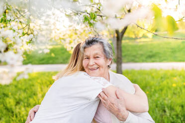 Elderly grandmother and an adult granddaughter outside in spring nature, hugging. - HPIF25338