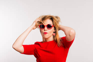 Portrait of a young beautiful woman with red sunglasses in studio, having fun. - HPIF25356