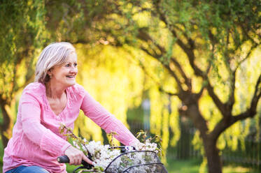 Schöne ältere Frau mit Fahrrad Radfahren draußen im Frühling Natur. - HPIF25382