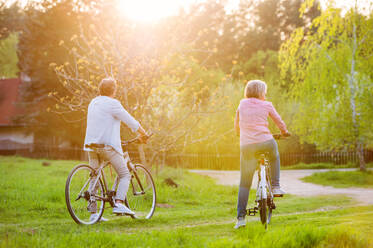 Schönes älteres Paar mit Fahrrädern draußen in der Natur beim Radfahren im Frühling. Rückansicht. - HPIF25389