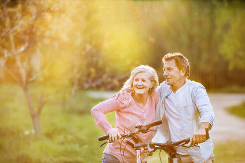 Beautiful senior couple with bicycles outside in spring nature. A man and woman in love. - HPIF25393