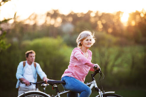 Beautiful senior couple with bicycles outside in spring nature cycling. - HPIF25400