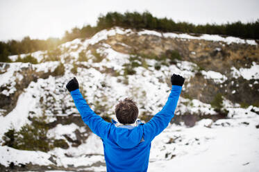 Älterer Mann joggt draußen in der winterlichen Natur, Hände hoch, Rückansicht. - HPIF25415