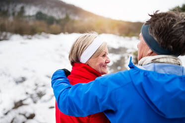 Älteres Paar joggt draußen in der winterlichen Natur und ruht sich aus. - HPIF25419