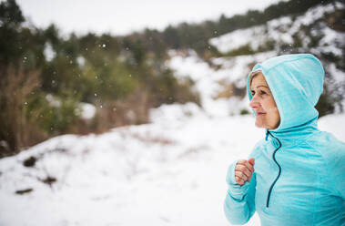 Ältere Frau joggt draußen in der winterlichen Natur. Raum kopieren. - HPIF25430