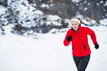 Ältere Frau joggt draußen in der winterlichen Natur. Raum kopieren. - HPIF25436