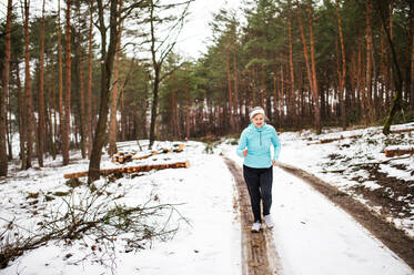 Ältere Frau joggt draußen in der winterlichen Natur. Raum kopieren. - HPIF25443