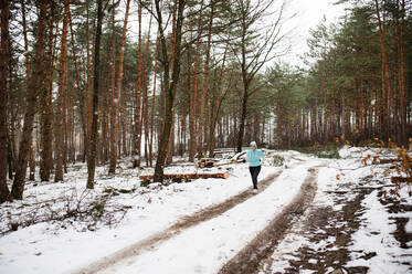 Ältere Frau joggt draußen in der winterlichen Natur. - HPIF25447
