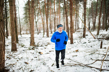 Senior Mann joggt draußen im Wald im Winter Natur. - HPIF25448