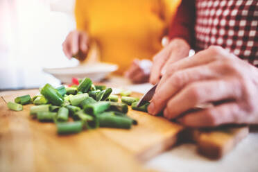 Unrecognizable senior man and woman preparing food in the kitchen. An old man chopping vegetables. - HPIF25552